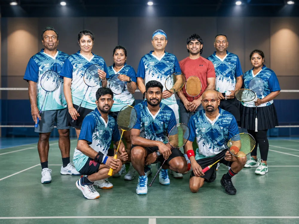 Team in blue jerseys lined up on court with rackets